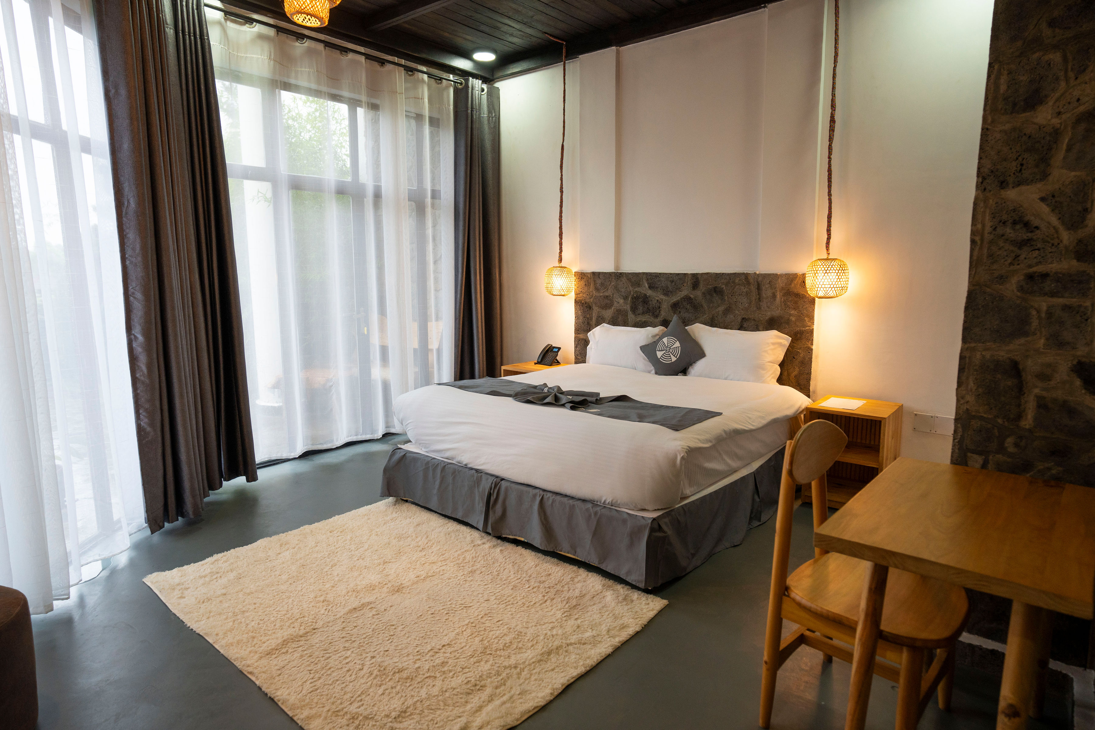 A highland room at Grotta Resort with warm pendant lamps and a stone feature wall